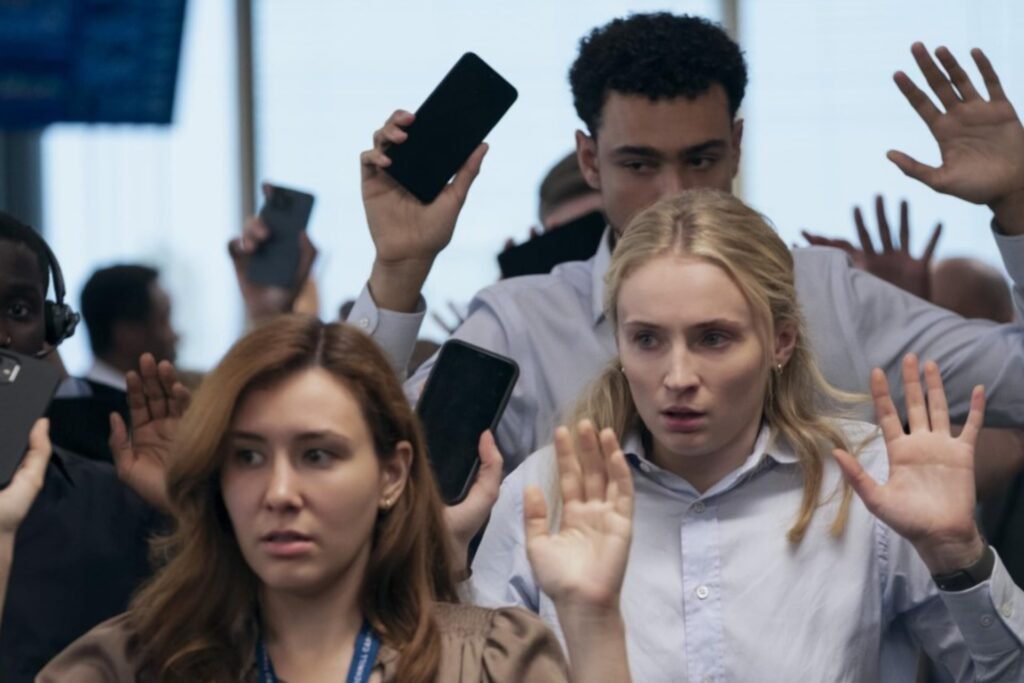 Archie Madekwe and Sophie Turner holding their hands up in an office building in Prime Video's Steal.