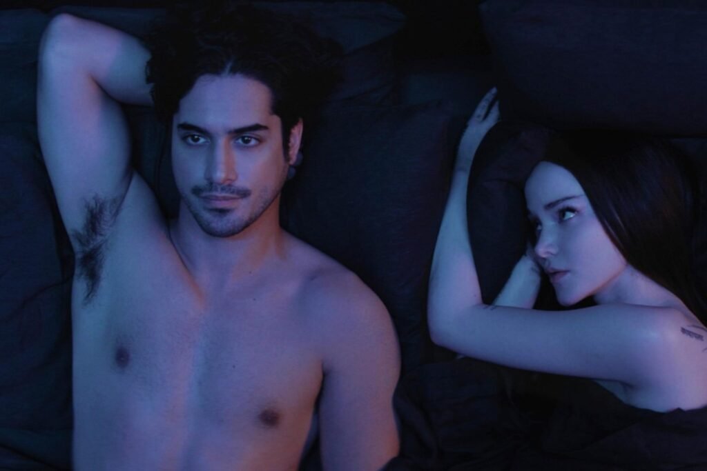 Dove Cameron and Avan Jogia lying in bed with inquisitive looks in Prime Video's 56 Days.