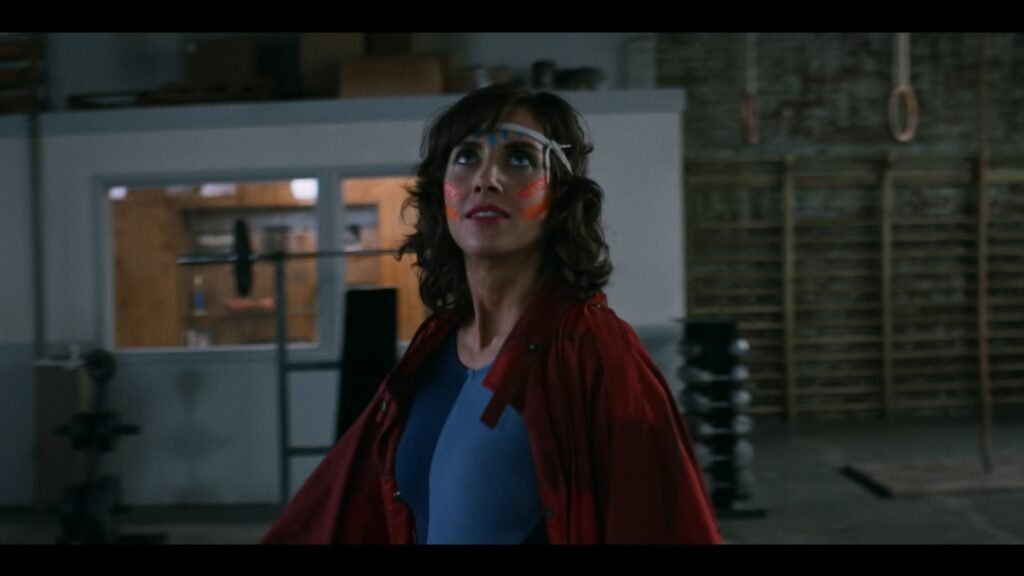 The lead in Glow wearing an ultimate warrior wrestling costume as she walks into the ring.