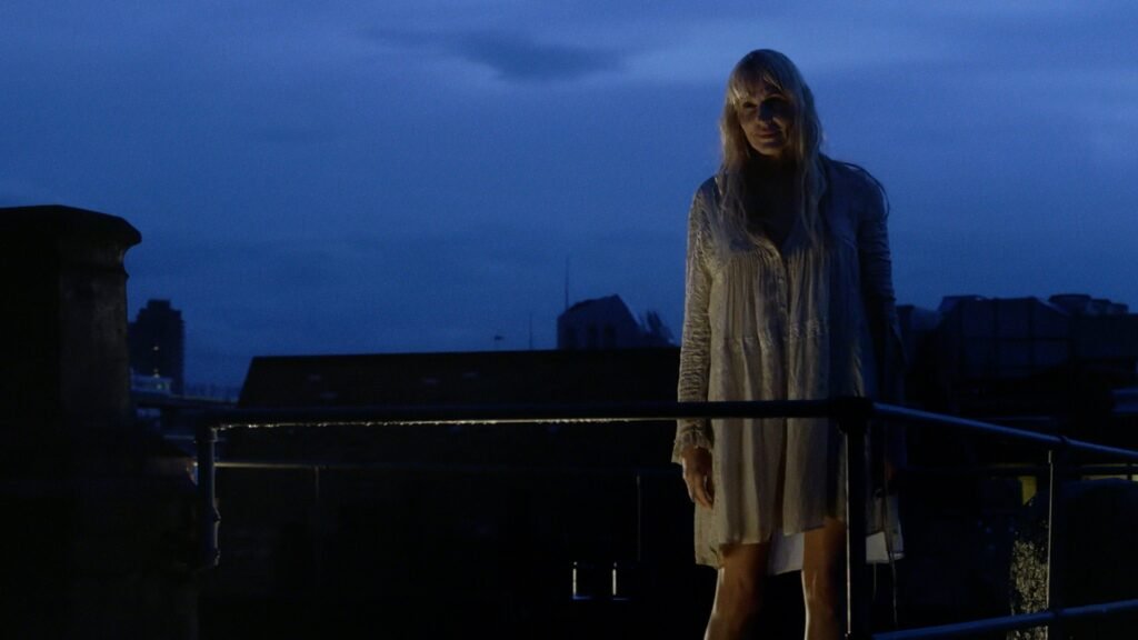 A blonde woman wearing white clothes stood on a roof in the sunset in Sense8.