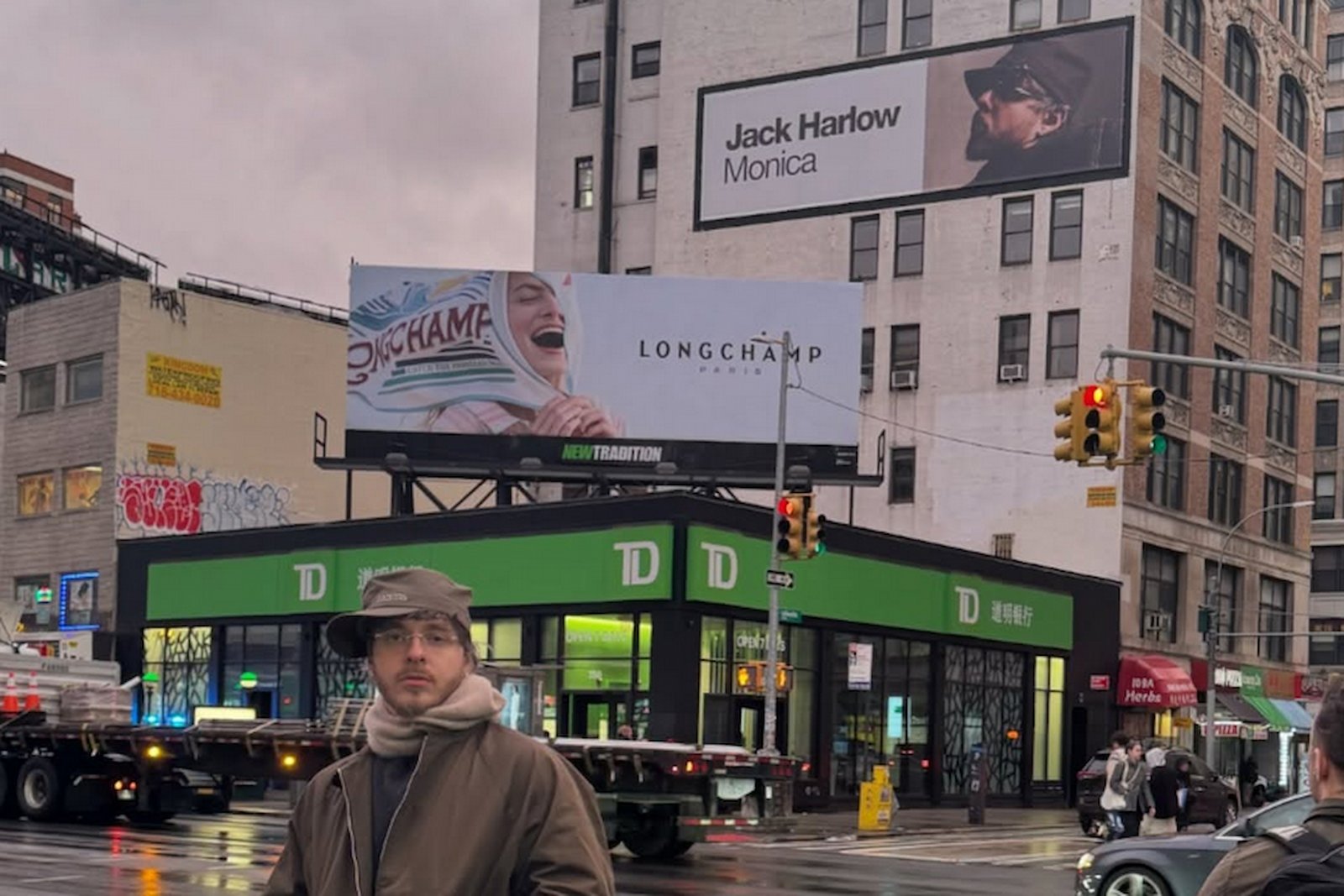 Jack Harlow standing in front of Monica billboard on the street